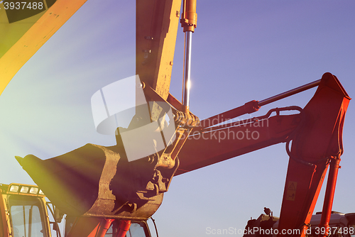 Image of Hydraulic excavator at work. Shovel bucket against blue sky