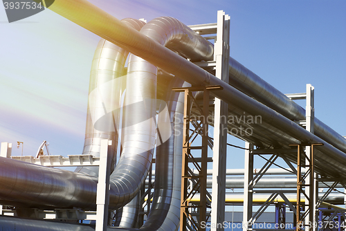 Image of industrial pipelines on pipe-bridge against blue sky