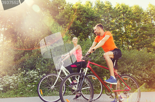 Image of happy couple riding bicycle outdoors