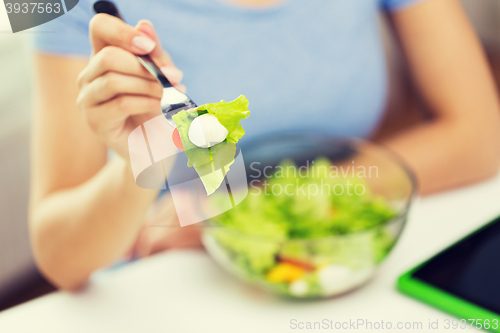 Image of close up of young woman eating salad at home