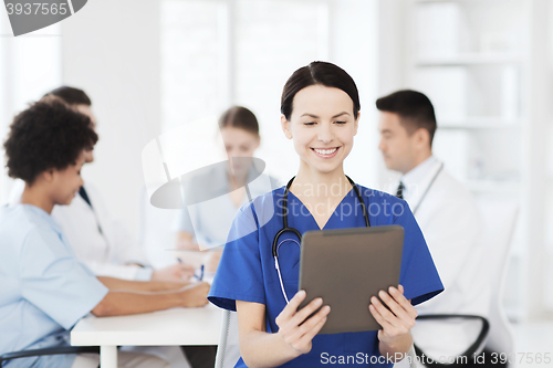 Image of happy doctor with tablet pc over team at clinic