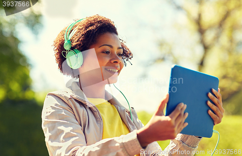 Image of happy african woman with tablet pc and headphones