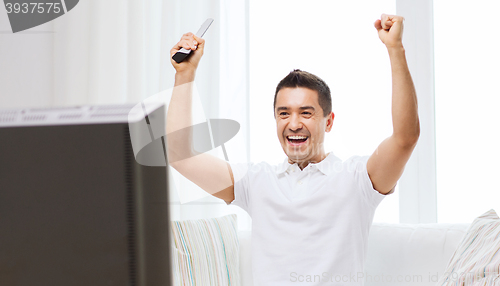 Image of smiling man watching sports at home