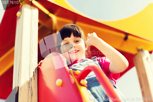 Image of happy little girl climbing on children playground