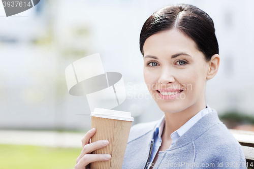 Image of smiling woman drinking coffee outdoors