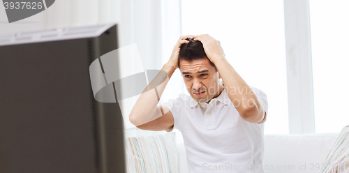 Image of disappointed man watching tv at home