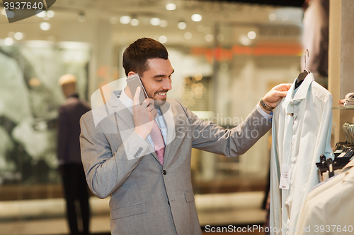 Image of happy man calling on smartphone at clothing store