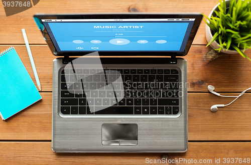 Image of close up of laptop with music player on table