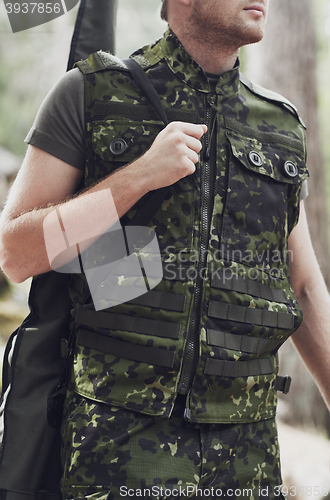 Image of close up of soldier or hunter with gun in forest