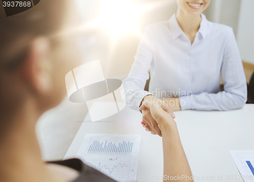 Image of two smiling businesswoman shaking hands in office