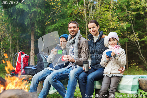 Image of happy family sitting on bench at camp fire