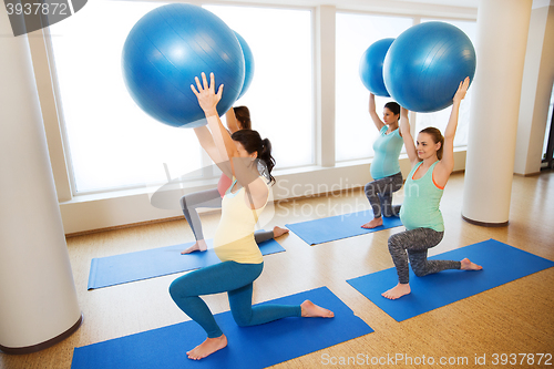 Image of happy pregnant women exercising with ball in gym