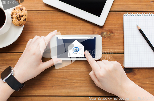 Image of close up of woman with smartphone on wooden table