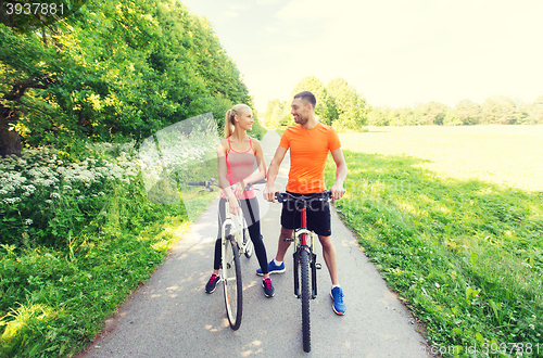 Image of happy couple riding bicycle outdoors