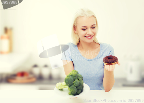 Image of smiling woman with broccoli and donut on kitchen