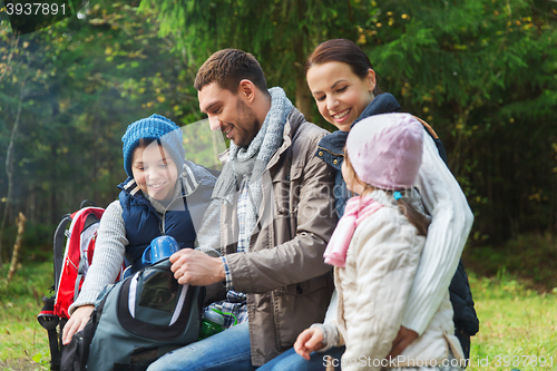 Image of happy family with backpacks and thermos at camp