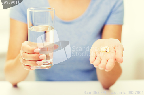 Image of close up of woman hands with pills and water