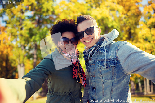 Image of happy teenage couple taking selfie on city street