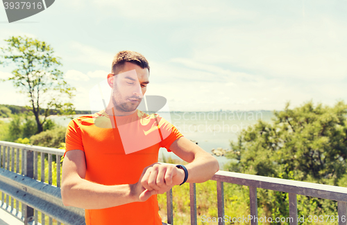 Image of young man with smart wristwatch at seaside