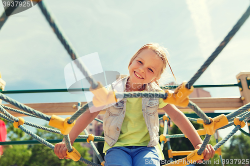 Image of happy little girl climbing on children playground