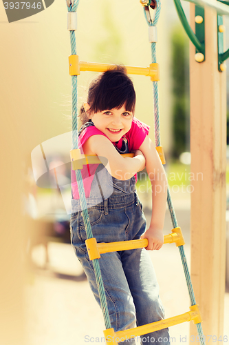 Image of happy little girl climbing on children playground