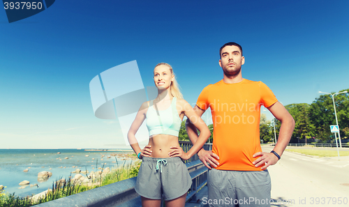 Image of happy couple exercising at summer seaside