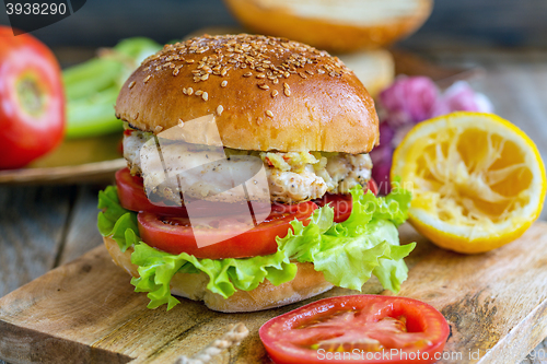 Image of Burger with vegetables, chicken and spicy sauce.