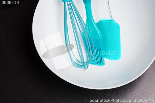 Image of Green silicone pastry brush and soup plate isolated on black