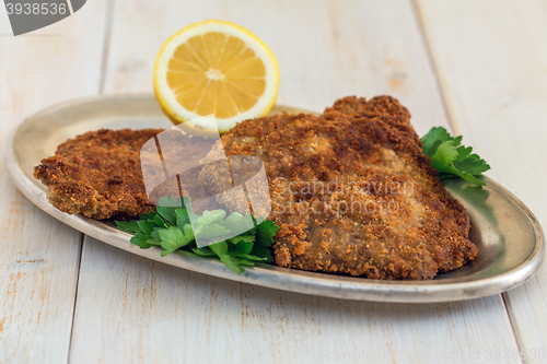 Image of Schnitzel beef with lemon on a metal tray.