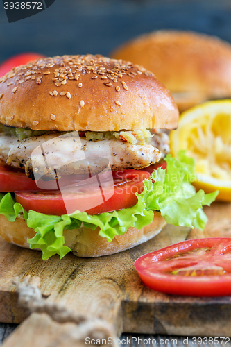 Image of Tasty burger with chicken, tomato and spicy sauce.