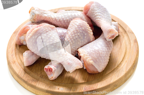 Image of Raw chicken drumsticks on a wooden board.