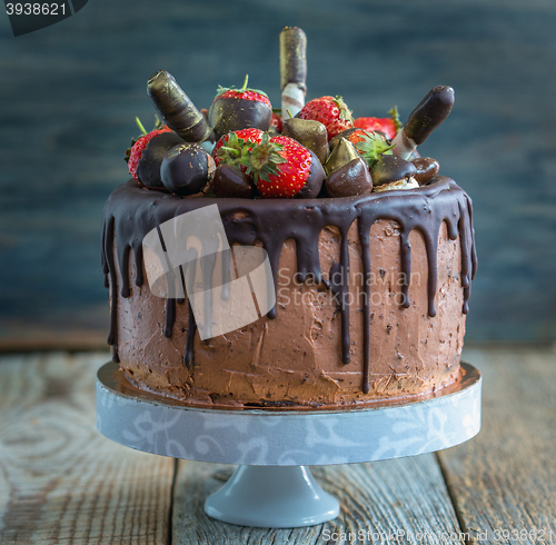 Image of Chocolate cake with strawberries, wafer rolls and candies.