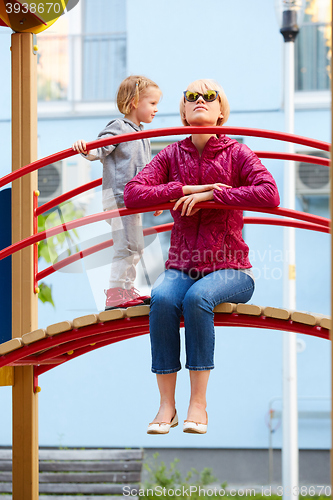 Image of Mother and daughter playing on the playground outdoors