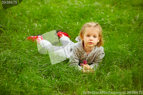 Image of Portrait of little girl lying on green grass