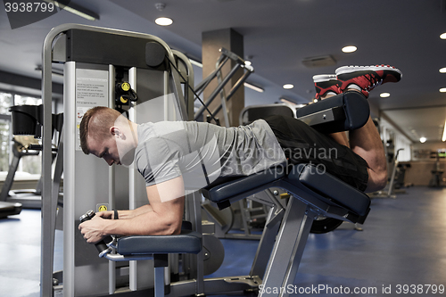 Image of man flexing leg muscles on gym machine