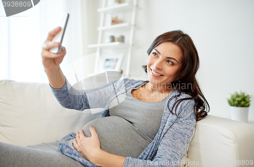 Image of pregnant woman taking smartphone selfie at home