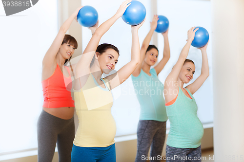 Image of happy pregnant women exercising with ball in gym