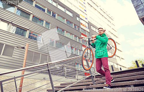 Image of young hipster man carrying fixed gear bike in city