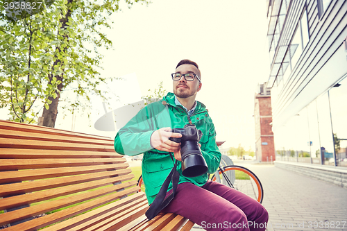 Image of young hipster man with digital camera in city