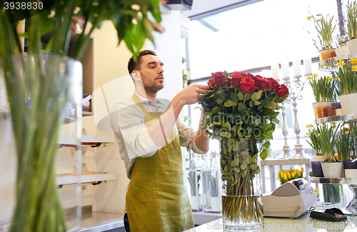 Image of smiling florist man with roses at flower shop