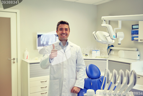 Image of happy male dentist showing thumbs up at clinic