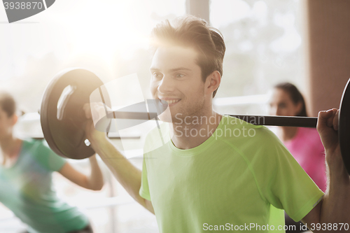 Image of group of people exercising with barbell in gym