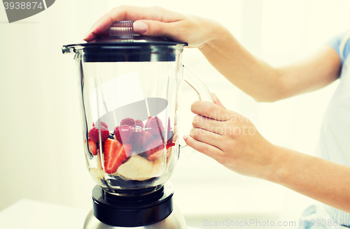 Image of close up of woman with blender making fruit shake