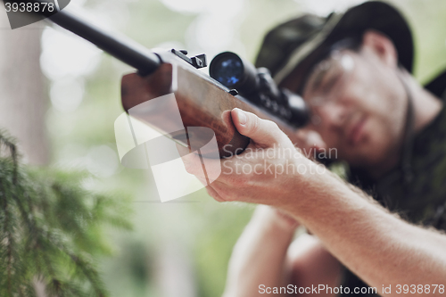 Image of soldier or hunter shooting with gun in forest