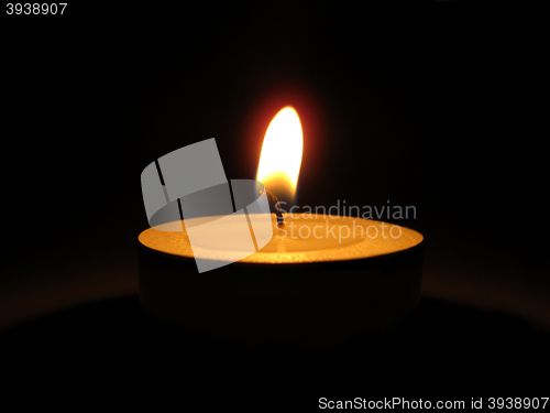 Image of Bright burning candle in the dark       
