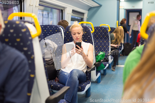 Image of Woman using mobile phone while travelling by train.