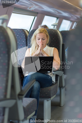 Image of Woman travelling by train working on laptop.