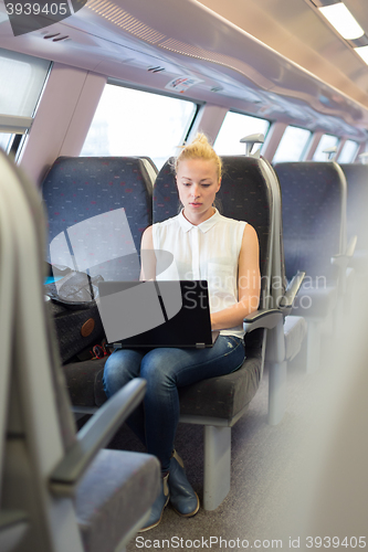 Image of Woman travelling by train working on laptop.