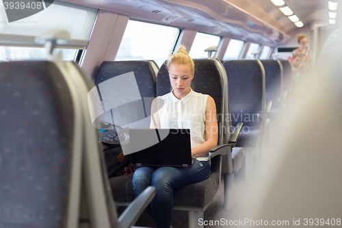 Image of Woman travelling by train working on laptop.
