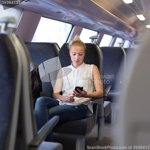 Image of Woman using mobile phone while travelling by train.
